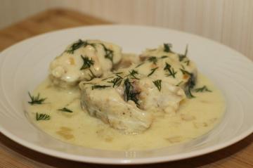 Alaska pollock with sour cream and garlic in a frying pan. Fish obtained by tender and juicy